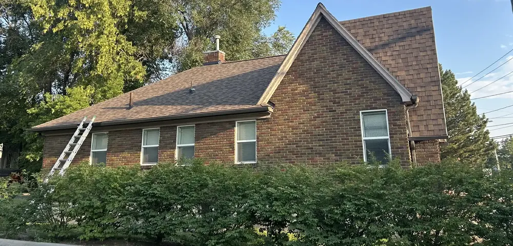 Brick home with asphalt shingle roof and ladder